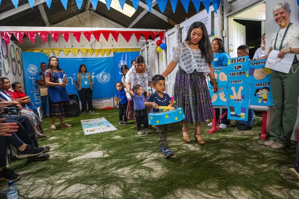 Children carry homemade instruments during an impromptu parade to welcome guests at a UNICEF-supported early childhood development center in Guatemala. 