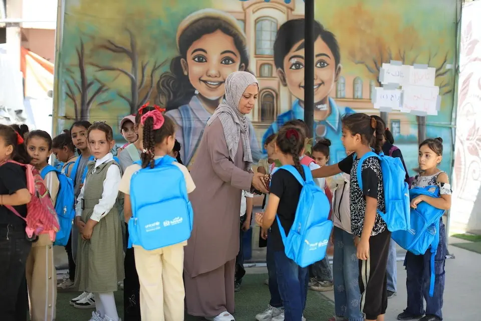 Children with UNICEF backpacks greet their new teacher on the first day of school in Gaza on Sept. 21, 2026.