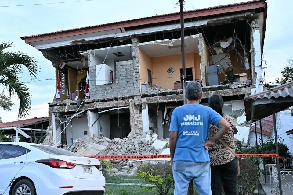 Man and woman look up at earthquake damaged home in Panama