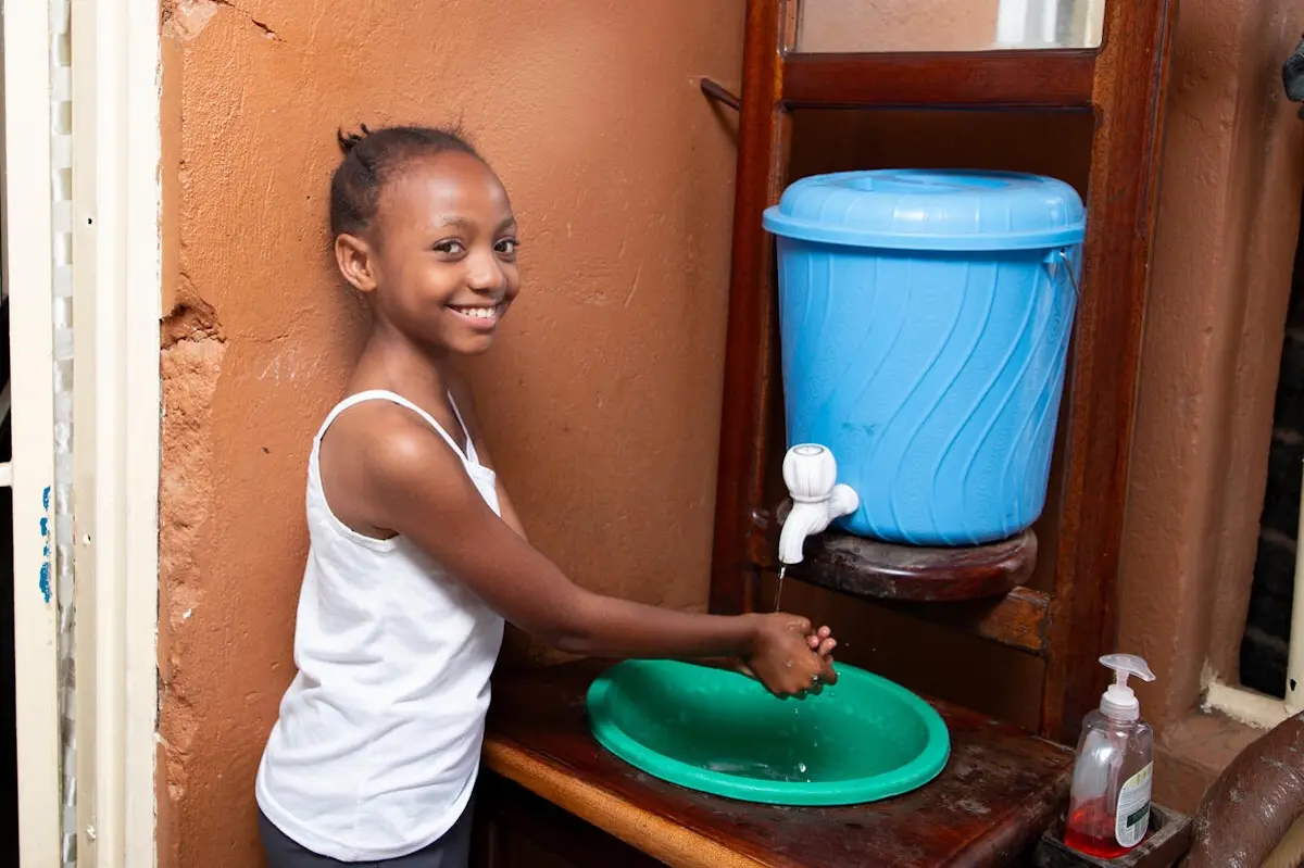 Ketsia, 10, washes her hands with soap and water at her home in Bunia, Democratic Republic of the Congo.