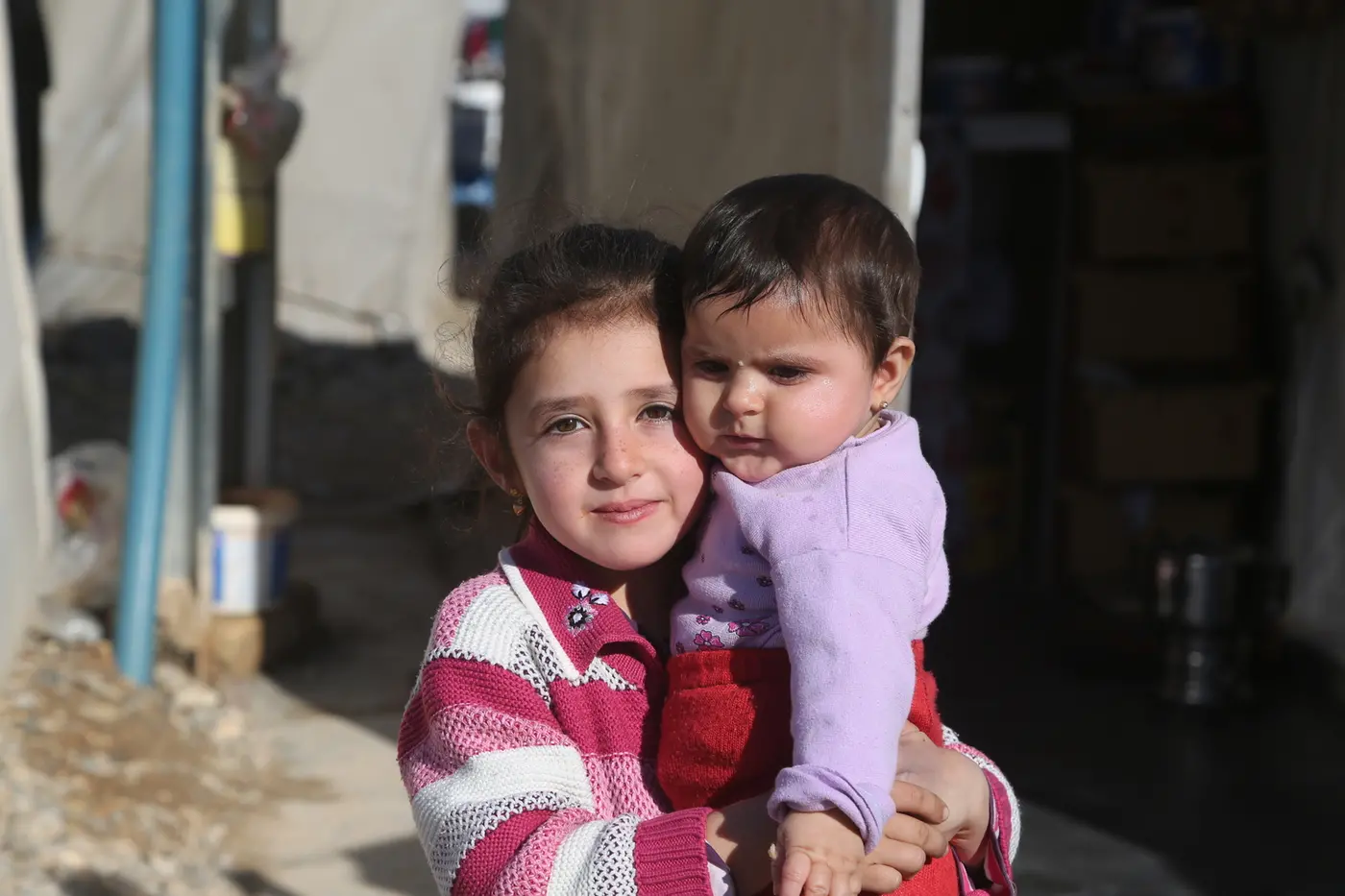 A girl carrying her baby sister in Nizip 1 refugee camp, Gaziantep, southern Turkey. Nizip 1 camp is home to over 10,000 Syrian refugees