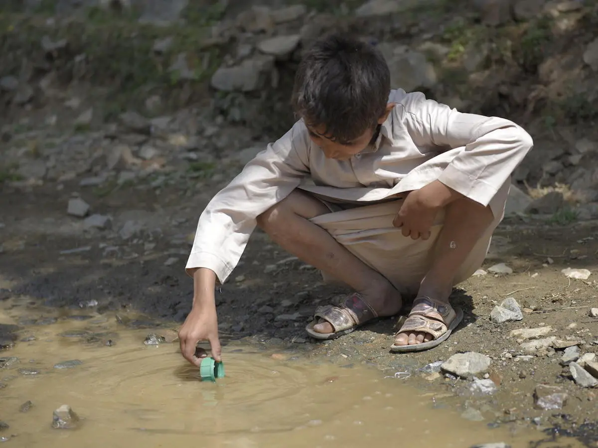 A child plays with a container cap in untreated water coming from a sewer pipe in Amran Governate, Yemen, October 2017.