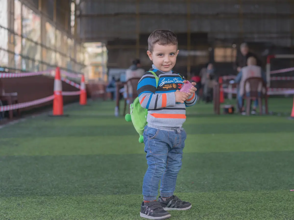 Syrian refugee child in Lebanon holds his mother's new LOUISE common card, which will allow the family to access all the cash-based aid programs for which they are eligible.
