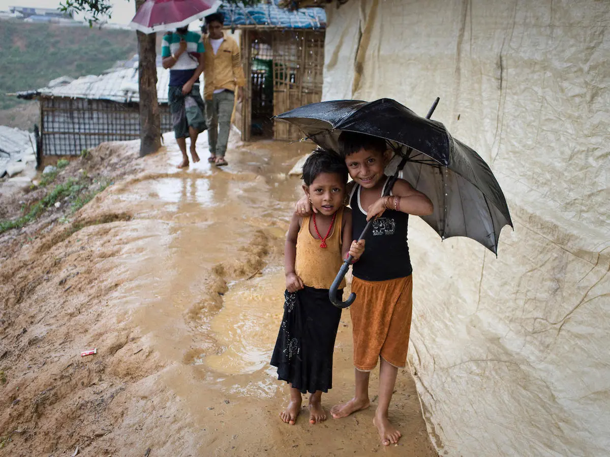 children smile as they shelter from the rain in Balukhali-Kutupalong, a refugee camp sheltering over 800,000 Rohingya refugees in Cox's Bazar, Bangladesh. 
