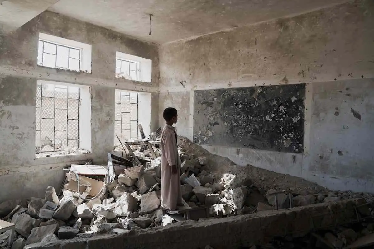 A student stands in the ruins of one of his former classrooms, which was destroyed in June 2015, at the Aal Okab school in Saada, Saada Governorate, Yemen, Monday 24 April 2017. Students now attend lessons in UNICEF tents nearby,