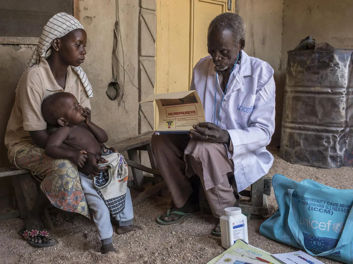 On January 13, 2020, Loveleen Anex, 25, holds her 9-month-old daughter, Ensteen, as UNICEF-supported health worker Benjamin Daniels does a general health check on the child in the village of Jarede, Adamawa state, Nigeria. 