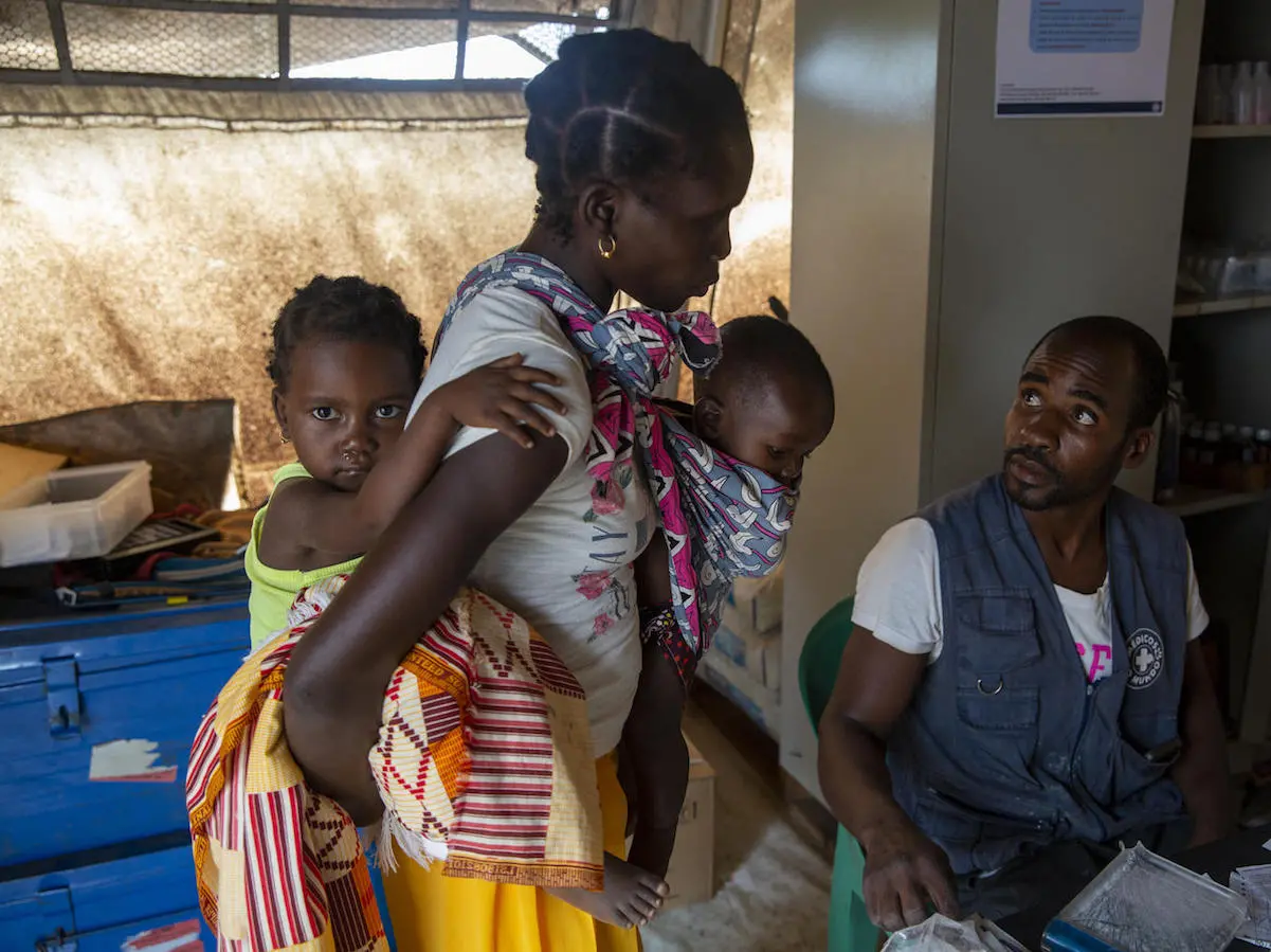 Eliza Arnaldo, 20, carries her children Natalia , 3, and Dominiqo, 6 months, to a UNICEF health center after they became feverish in the Ndjenja resettlement camp, Mozambique, March 4, 2020.