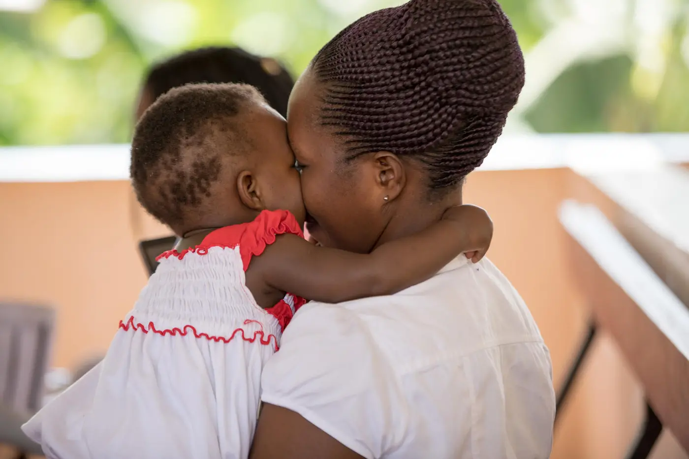 Emily Aceng, 1 year, smiles back at her mother's play as they await immunization services at Kiswa Health Centre III in Uganda.
