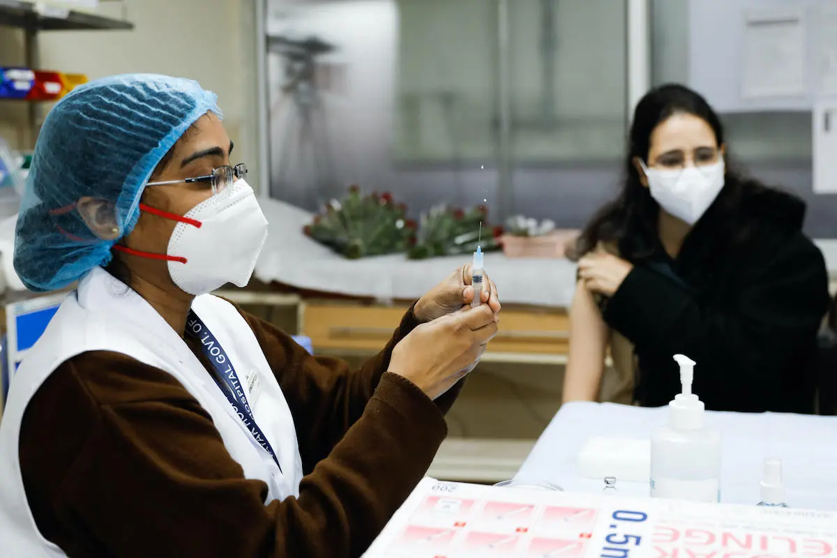 A vaccinator administers a COVID-19 vaccine to a health worker at Lok Nayak Hospital in New Delhi, India.