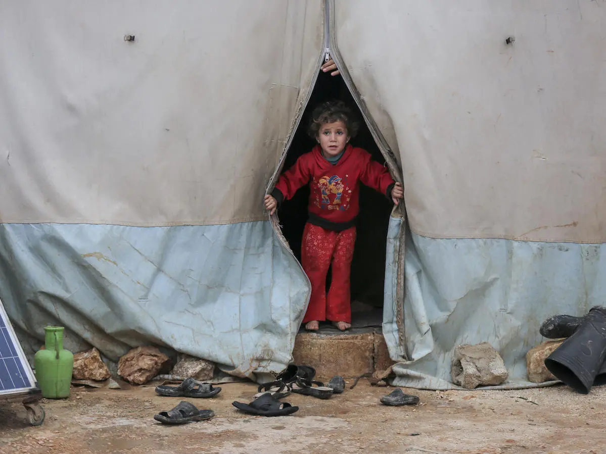 On 19 January 2021, a child looks out a tent in Kafr Losin Camp in northwest Syrian Arab Republic. UNICEF is working with partners to provide displaced children in Syria with the supplies and services they need to survive and thrive. 