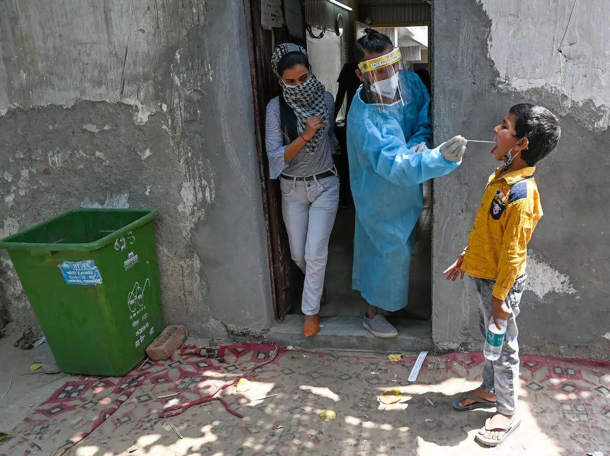 A medical worker takes a swab sample of a boy for a Reverse Transcription Polymerase Chain Reaction (RT-PCR) test at a COVID-19 testing center in Ghaziabad, India on April 29, 2021. 