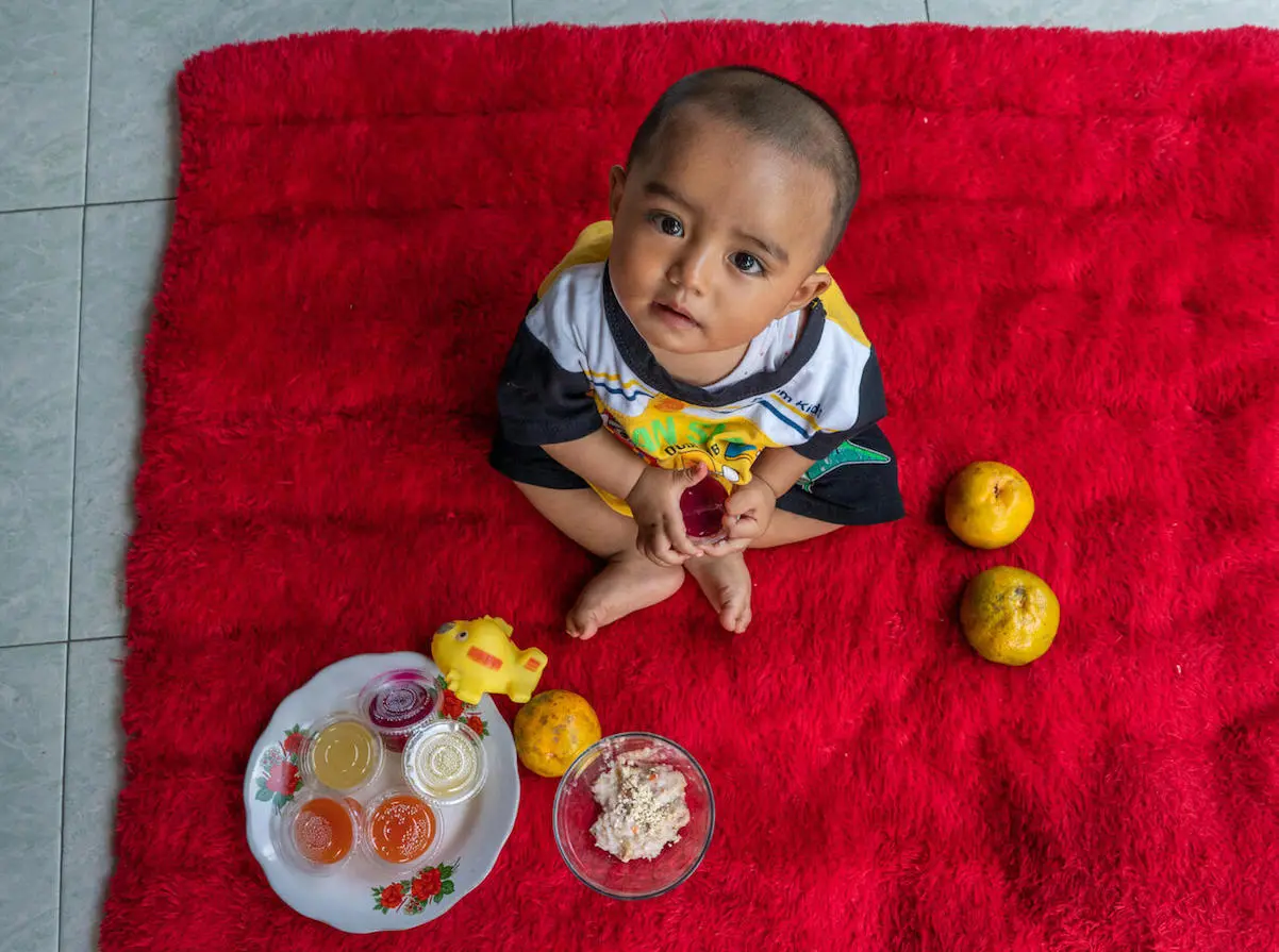 Eight-month-old Sakha holds a cup of dragon fruit pudding at his home in Pasung Village, Klaten, Central Java Province, Indonesia on September 7, 2021. Eight-month-old Sakha holds a cup of dragon fruit pudding at his home in Pasung Village, Klaten, Central Java Province, Indonesia on September 7, 2021.