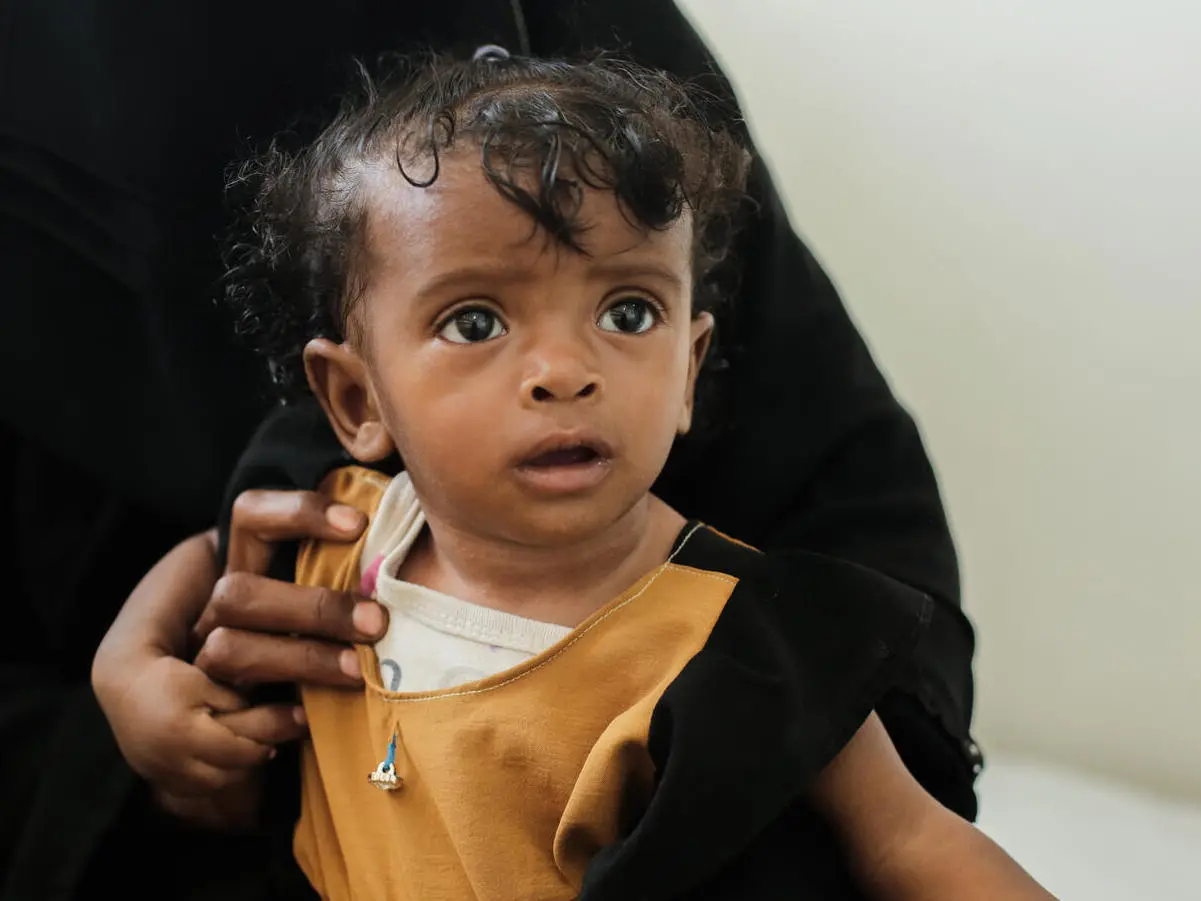A child waits with her caregiver to receive treatment for severe acute malnutrition