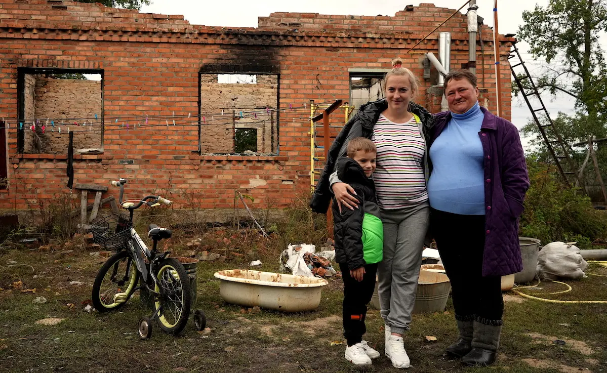 A 6-year-old boy stands with his mother and grandmother outside the house that was destroyed during a heavy shelling attack in Shybene, Kyiv oblast, Ukraine.