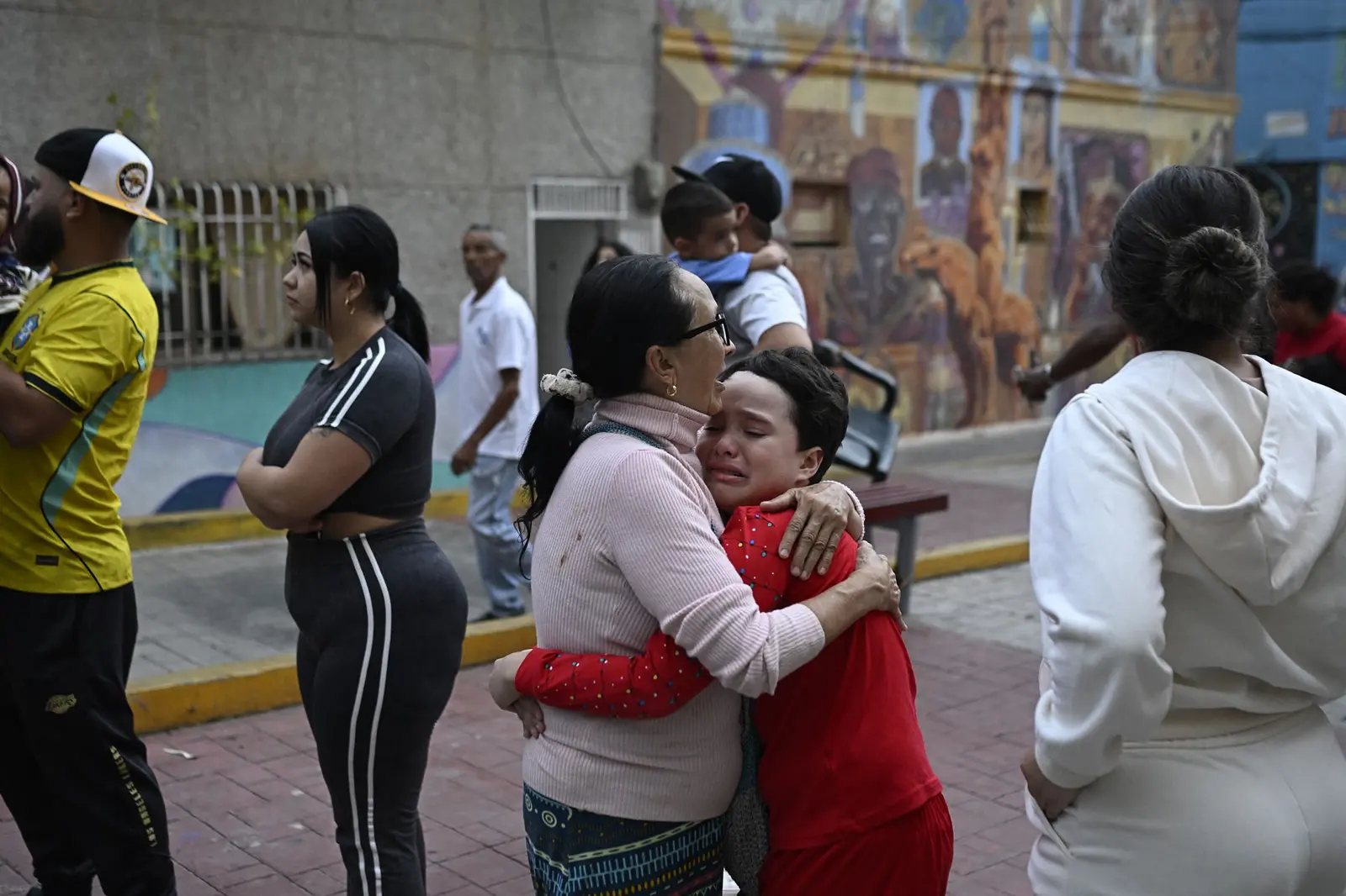 A woman comforts a child in the street following an earthquake in Caracas