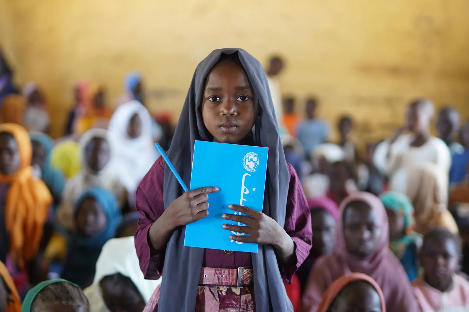 Child holding a notebook in front of his chest