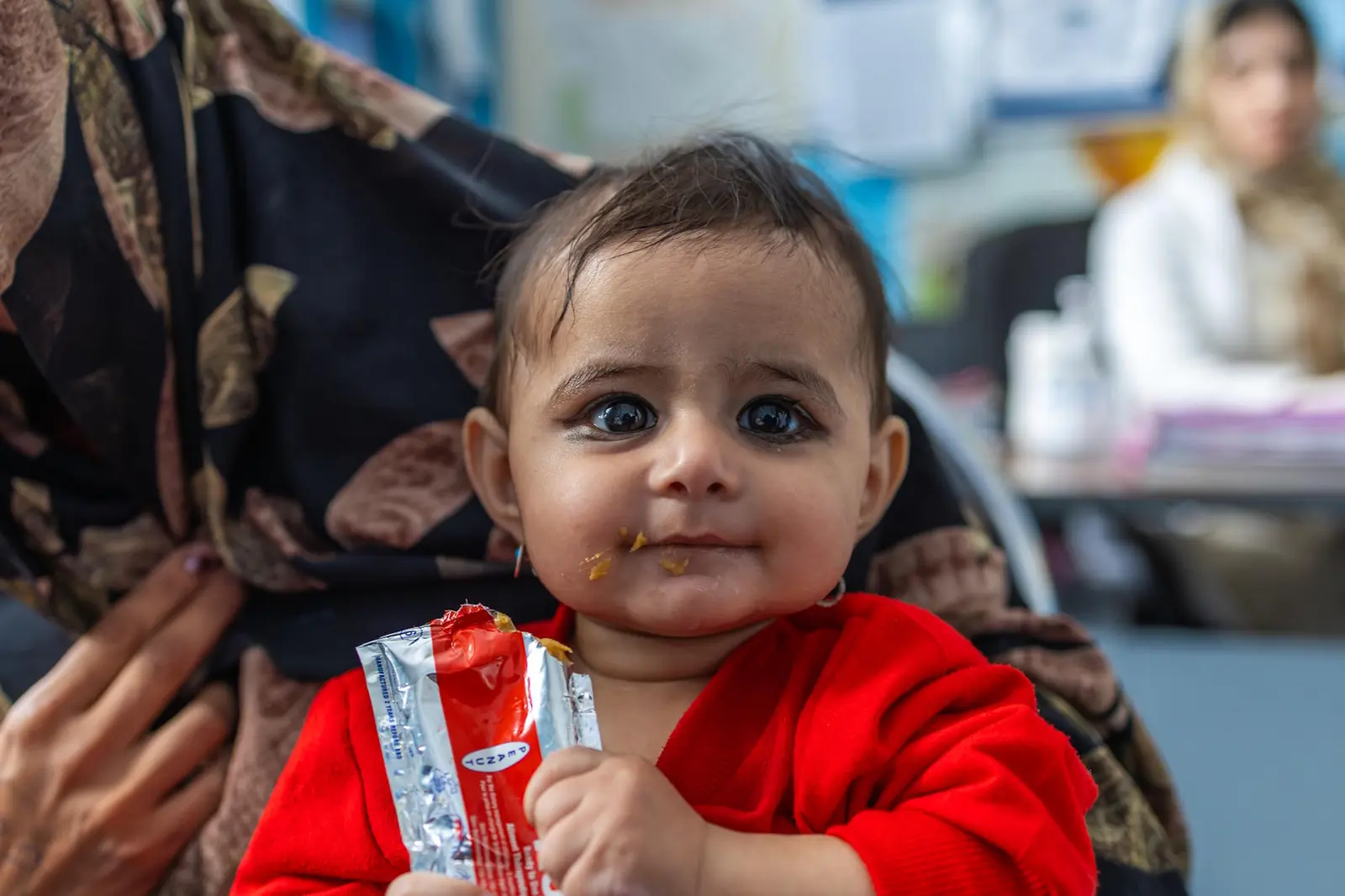 Young girl smiling and eating a RUTF packet