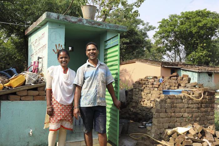 Raimuni, 28, stands with her husband outside the toilet she built in their home as part of a UNICEF sanitation program in Jharkhand, India. 