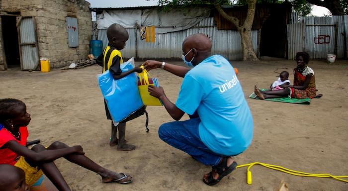 Bachuy Kier, who runs the UNICEF child protection programs in Pibor, South Sudan, hands a reintegration kit to a child who is about to be reunited with family. 
