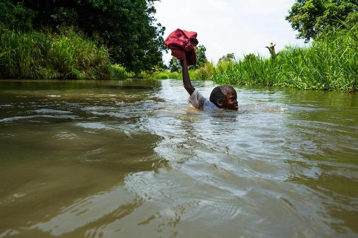 A student swims across a flooded path on his way home from school in Walawalang village, Juba, South Sudan.