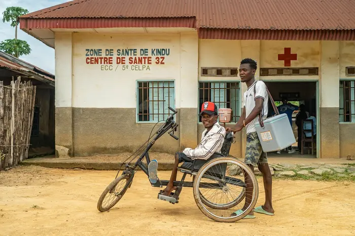 From left: Rajabu Vambise, 27, polio survivor and UNICEF-supported community worker, with a vaccinator during a polio vaccination campaign in Kindu, Maniema province, Democratic Republic of the Congo, on March 30, 2024.