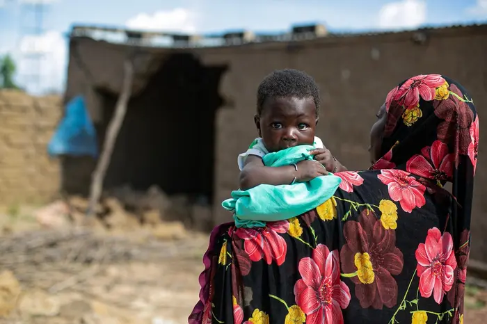 A mother holds her 2-month-old infant outside the flood-damaged family home in Sirebougou village, S&eacute;gou region, Mali.
