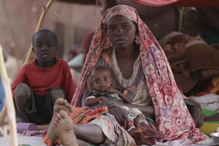 A mother holds her baby son in a temporary shelter in Tawila, North Darfur, Sudan on April 15, 2025. 