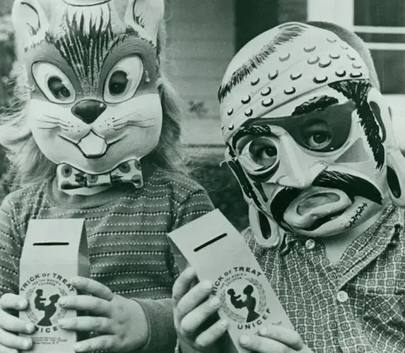 Children wearing Halloween masks holding Trick-or-Treat for UNICEF collection boxes.