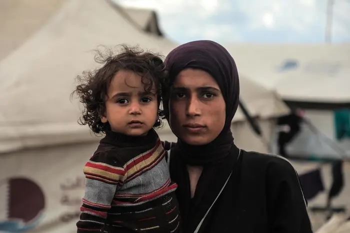 A mother holds one of her children in a displacement camp in Gaza in November 2025.