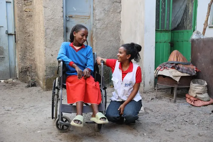 Kibra, 15, sits in her wheelchair next to Mikal, a social worker supported by UNICEF, outside Kibra's home in Tigray, Ethiopia.