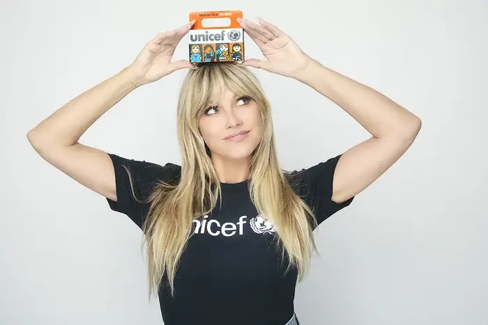 Heidi Klum holds the iconic Trick-or-Treat for UNICEF orange box during 75th anniversary campaign.