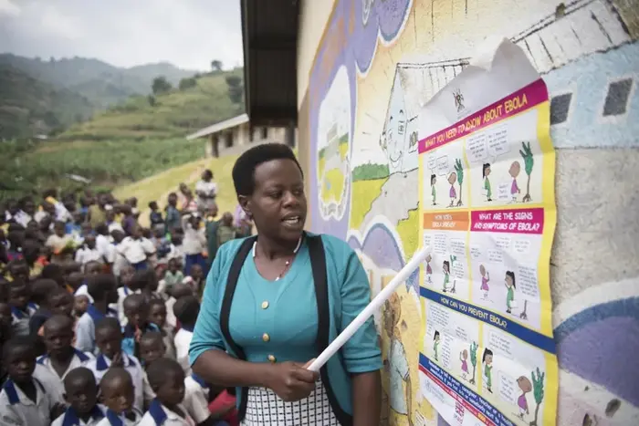 A woman shares information about Ebola with community members in Uganda.