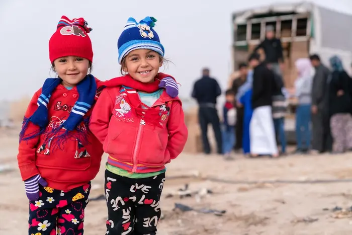 Two Syrian refugee girls wear winter gear provided by UNICEF.