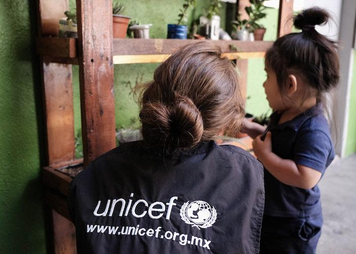 A UNICEF worker plays with a toddler at a shelter in Tijuana, where her family is waiting for their U.S. asylum application to be processed. 
