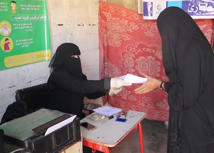 A woman receives her emergency cash transfer payment from a UNICEF-supported worker in Yemen's Sada'a region. The payment allows families to buy lifesaving essentials. 