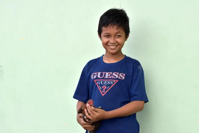Rivaldi, 13, holds one of his six chickens outside the family home in Palu, Central Sulawesi. After he finishes school, he wants to be a chicken and goat farmer.
