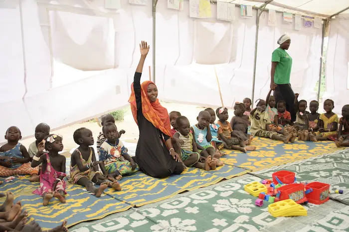 A UNICEF-trained teacher leads a group of students in a song at an Early Childhood Development Center in Kenya's Kakuma Refugee Camp. unicef, unicef usa, kakuma, kenya, refugee camp, refugees, early childhood development