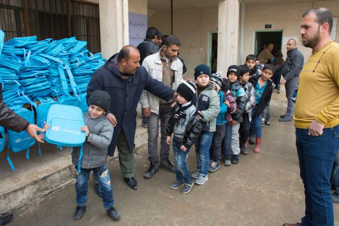 Children line up to receive backpacks supplied by UNICEF at Koofa Boys School, eastern Mosul, Iraq.