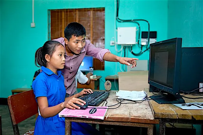 Anamika Chakma, 10 when this photo was taken, is helped by her teacher to learn how to use a computer in a UNICEF-supported Child Friendly Schools program in Bangladesh