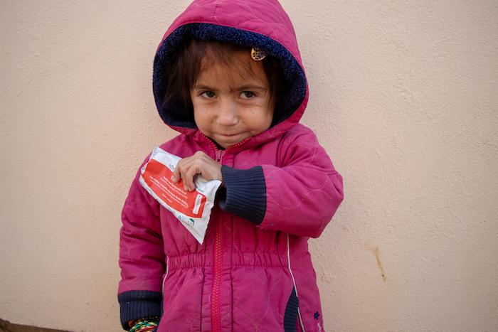 Parwana, 4, holds a sachet of Ready-to-Use Therapeutic Food, a fortified peanut paste that is helping her recover from severe acute malnutrition.