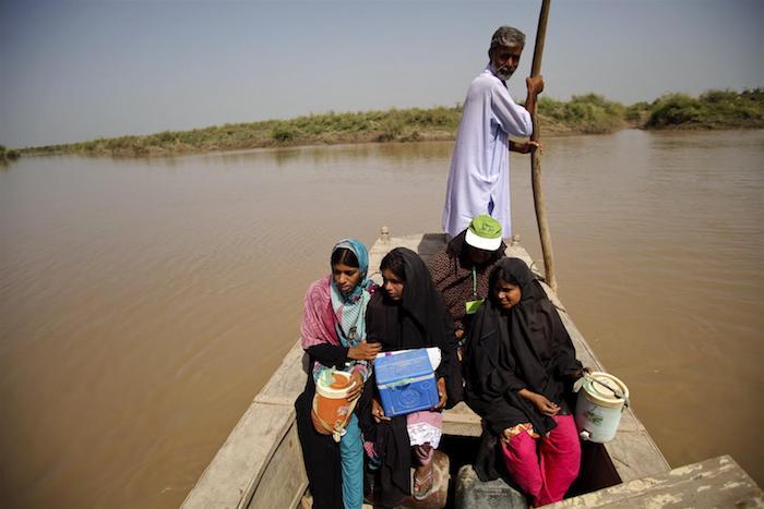 UNICEF-supported health workers cross the Indus River to a flooded village to vaccinate young children. One of them carries an insulated ‘cold box' to keep vaccines at a constant low temperature to maintain their potency. 