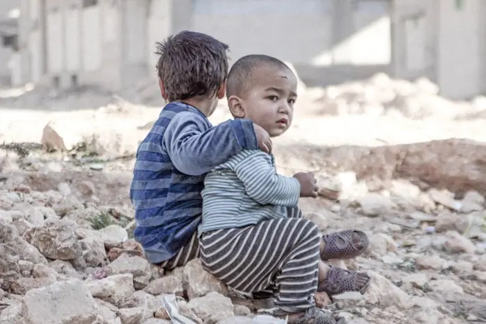 Syrian Arab Republic, Esraa, 4, and her brother Waleed, 3, sit on the ground near a shelter for internally displaced persons