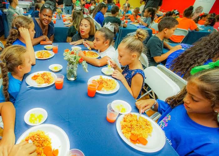UNICEF USA's Anucha Brown (left) and Olga Ramos, President of the Boys &amp; Girls Clubs of Puerto Rico, talk with kids enjoying dinner at the Las Margaritas Club.