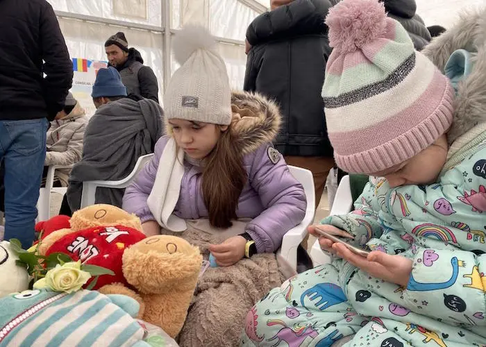 Masha, left, and Dasha play games on mobile devices after arriving in Isaccea, Romania, with their mother. Masha, left, and Dasha play games on mobile devices after arriving in Isaccea, Romania, with their mother.