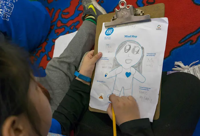 Students in Ms. Ng's class use a UNICEF Kid Power Mind Map to write about how they are being helpers in their own community.