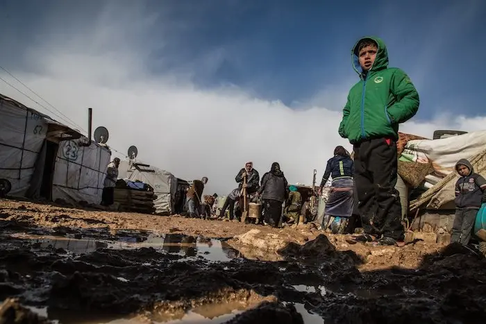A Syrian refugee child, photographed in January 2018, wearing sandals and standing in mud at an informal settlement in Haoush Harime, in the Bekaa Valley, Lebanon.