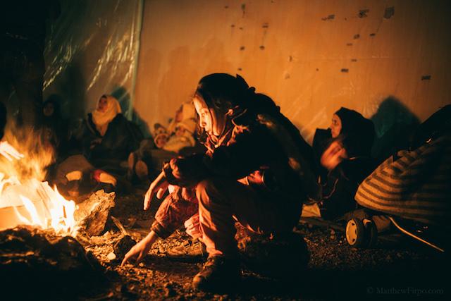 Refugees staying warm on the shores of Greece.