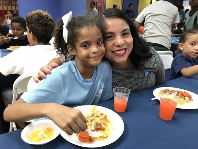 Michelle Centeno, manager of UNICEF USA's response in Puerto Rico post-Hurricane Maria, right, sits with 7-year-old Noyaris, a beneficiary of a nutrition program launched in September at Boys &amp; Girls Clubs of Puerto Rico with UNICEF USA's support.