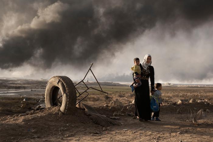 A displaced woman walks with two children south of Mosul, Iraq in 2016. 