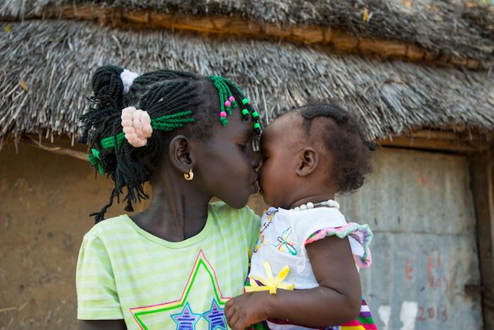 In October 2015, Nyayjaw, 8, kisses her baby sister Nyagua, whom she just met today, after being reunited with her mother in South Sudan. UNICEF helped reuinite the family after they were separated by conflict for two years.